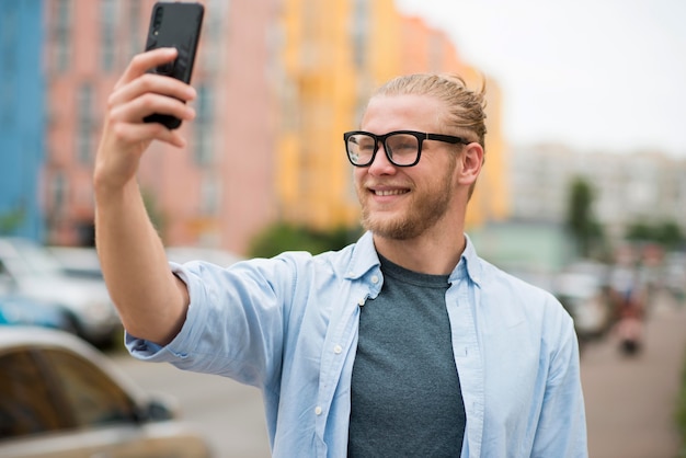 Hombre sonriente al aire libre tomando una selfie