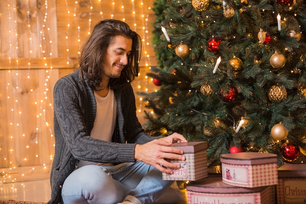 Hombre sonriente al lado de árbol de navidad