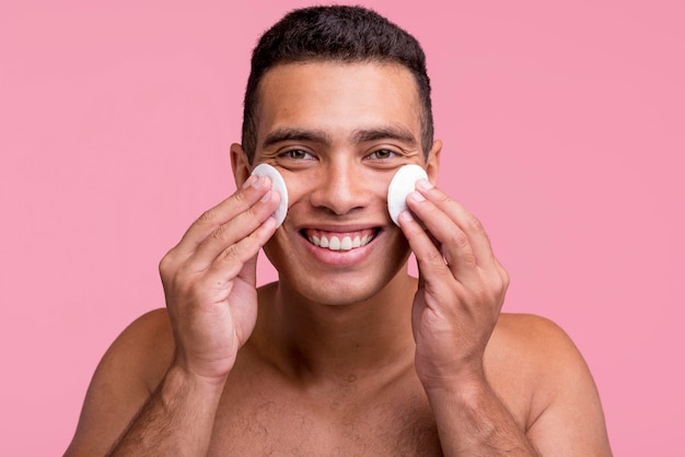 Hombre sonriente con almohadillas de algodón en la cara