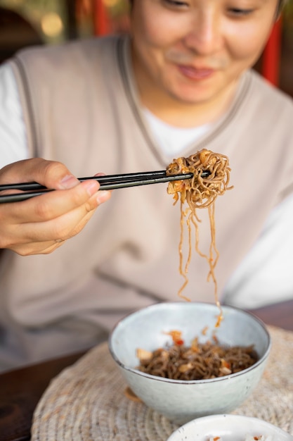 Foto gratuita hombre sonriente de alto ángulo comiendo fideos