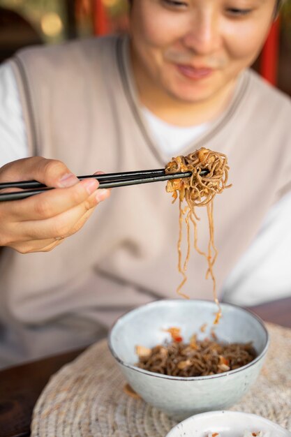 Hombre sonriente de alto ángulo comiendo fideos