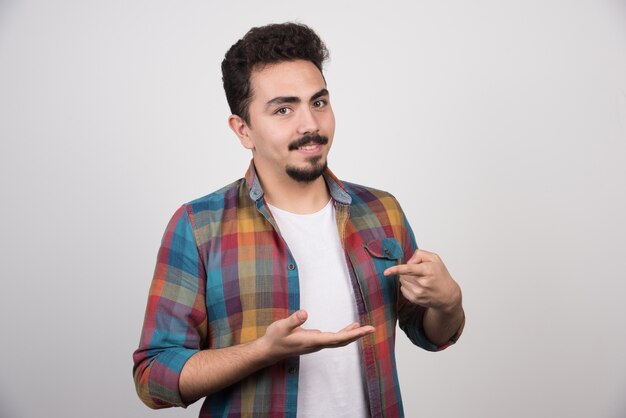 El hombre sonriente apunta su dedo a su mano vacía.