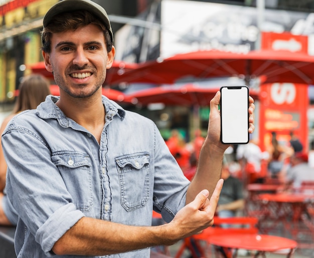 Foto gratuita hombre sonriente apuntando a teléfono inteligente