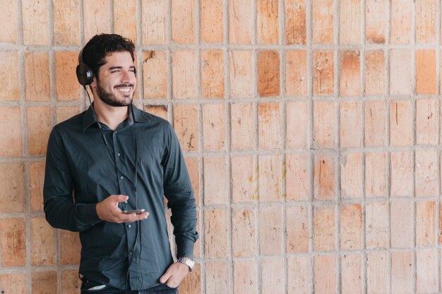 Hombre sonriente en auriculares posando con teléfono