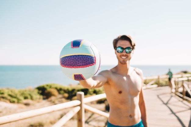 Foto gratuita hombre sonriente con balonvolea en la playa