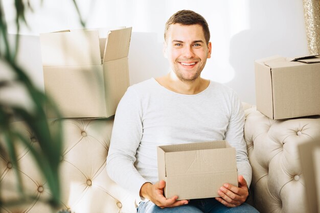 Hombre sonriente con caja en el apartamento