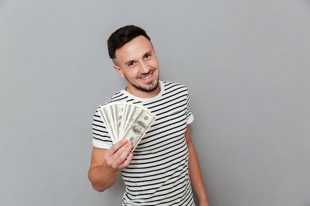 Hombre sonriente en camiseta con dinero y mirando a cámara