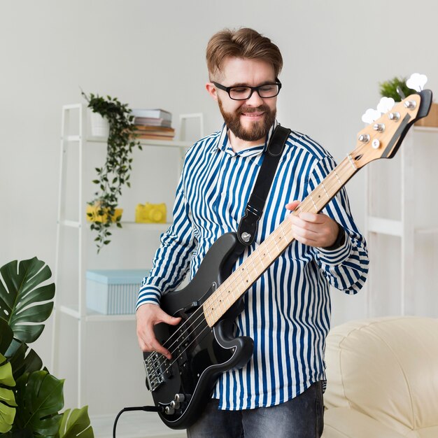 Hombre sonriente en casa con guitarra eléctrica