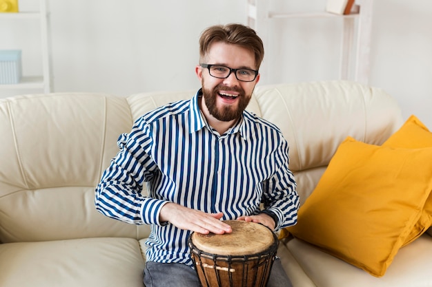 Foto gratuita hombre sonriente en casa con tambor