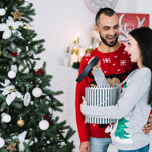 Hombre sonriente cerca de la mujer con el regalo