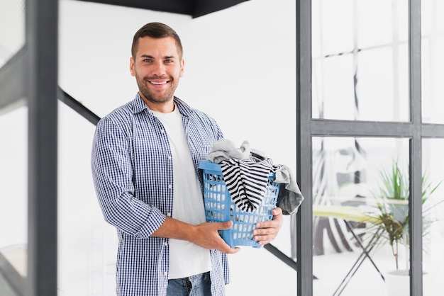 Hombre sonriente con cesta llena de ropa