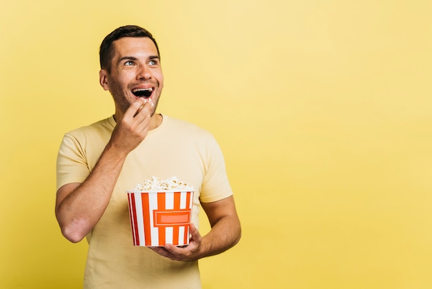 Hombre sonriente comiendo palomitas de maíz con espacio de copia