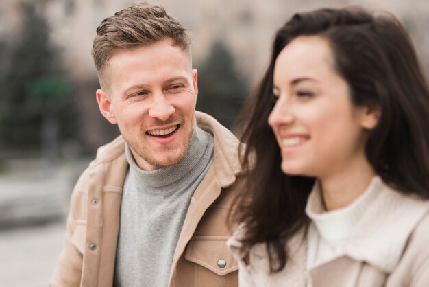 Hombre sonriente conversando con mujer al aire libre