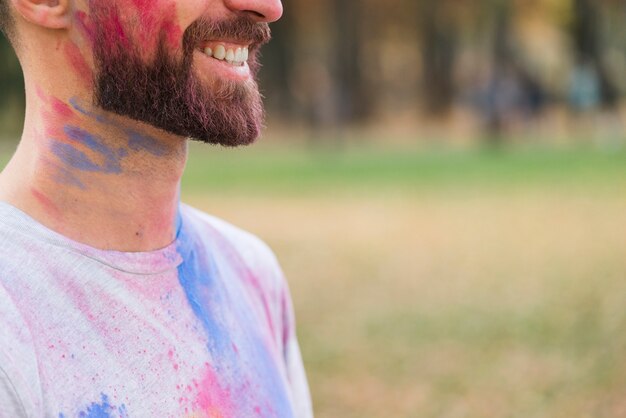 Hombre sonriente cubierto de pintura multicolor