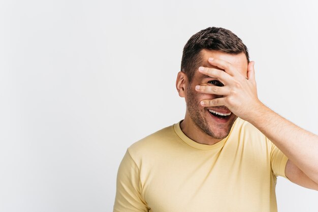 Hombre sonriente cubriéndose la cara con espacio de copia