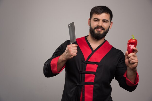 Hombre sonriente con cuchillo y pimiento rojo.