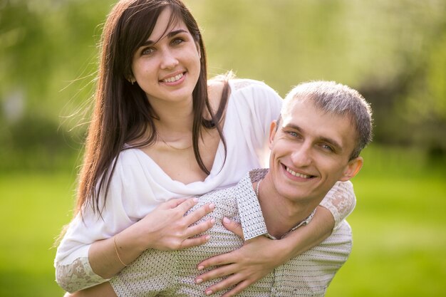 Hombre sonriente dando un paseo a caballito a su novia