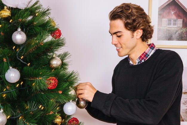 Hombre sonriente decorando árbol de navidad