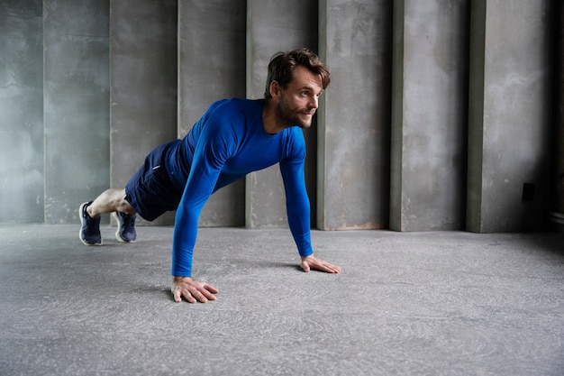 Foto gratuita hombre sonriente deportivo de tiro completo haciendo ejercicio en interiores