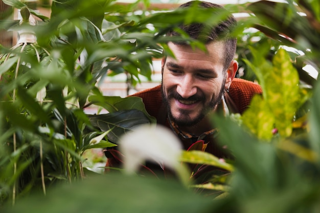 Hombre sonriente detrás de las plantas