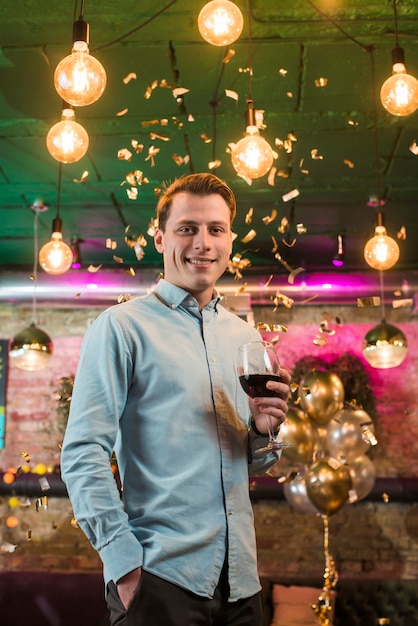 Hombre sonriente disfrutando en fiesta con copa de vino