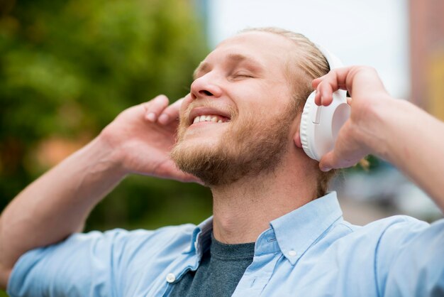 Hombre sonriente disfrutando de música en auriculares