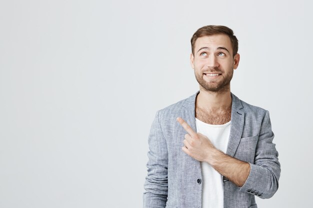 Hombre sonriente emocionado que señala en la esquina superior izquierda del anuncio