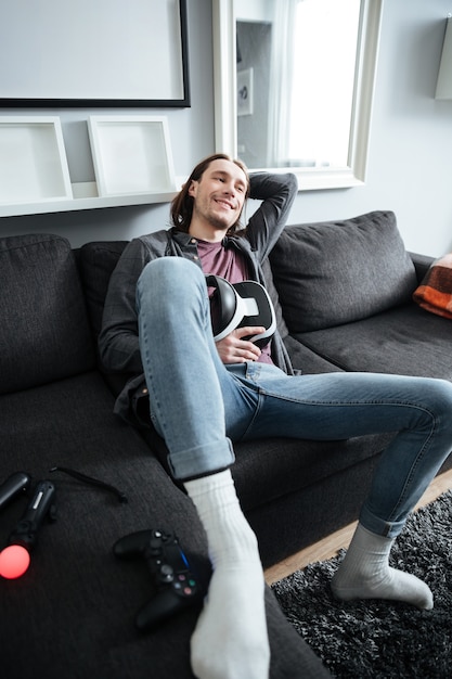 Hombre sonriente se encuentra en el sofá en casa en el interior