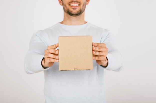 Hombre sonriente entregando una caja de cartón