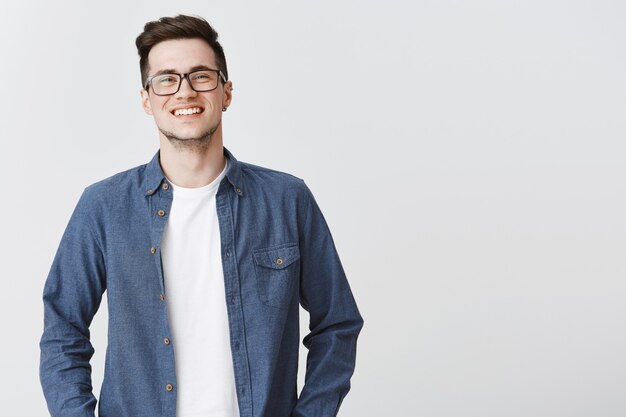 Hombre sonriente entusiasta que parece feliz con gafas y ropa casual