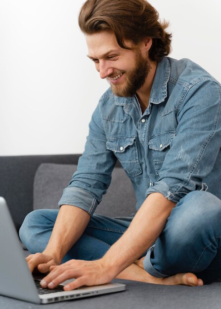 Hombre sonriente escribiendo en el teclado del portátil