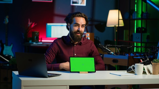 Hombre sonriente en el estudio filmando chroma key tableta revisión para entusiastas de la tecnología