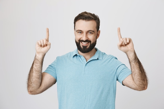 Hombre sonriente feliz apuntando hacia arriba