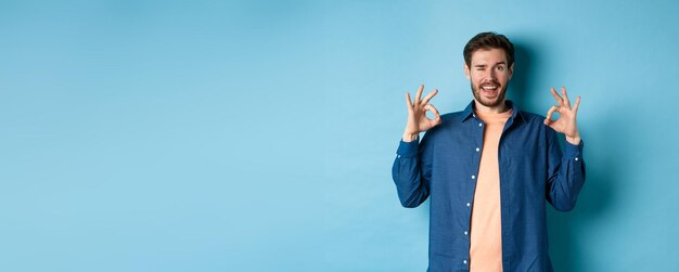 Hombre sonriente feliz guiñando un ojo y mostrando bien ok signo decir sí aprobar y estar de acuerdo con algo bueno st