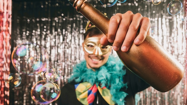 Hombre sonriente en fiesta de carnaval con botella de champagne