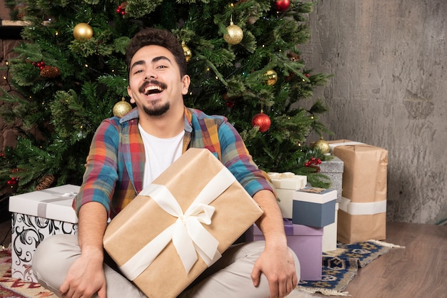 Hombre sonriente con ganas de conocer el interior de la caja de regalo.