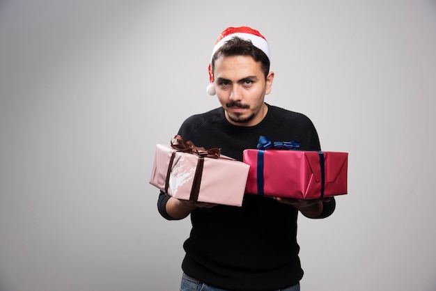 Foto gratuita un hombre sonriente con un gorro de papá noel con regalos de año nuevo.