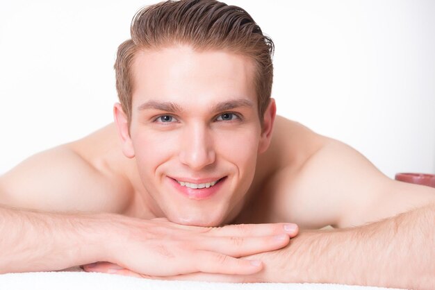 Hombre sonriente guapo acostado en las mesas de masaje en el salón de spa y relajarse. Concepto de tratamiento de belleza.