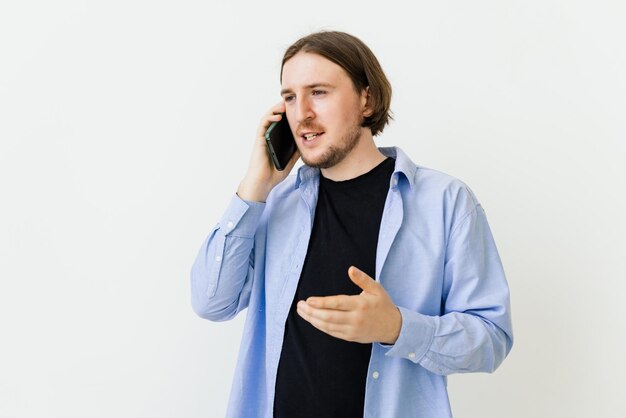 Hombre sonriente hablando por un teléfono móvil aislado sobre fondo blanco.