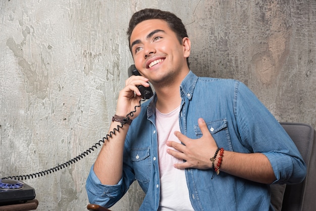 Foto gratuita hombre sonriente hablando por teléfono y sentado en una silla. foto de alta calidad