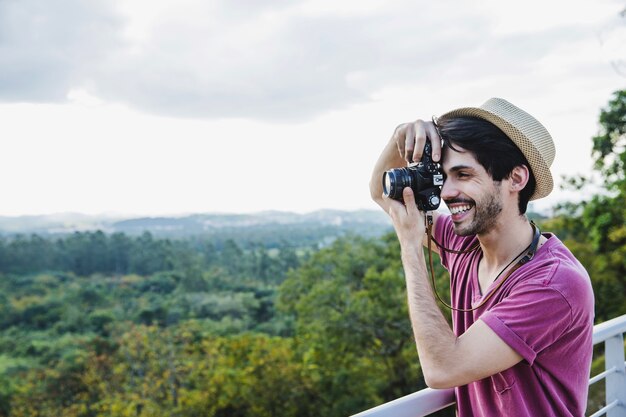 Hombre sonriente haciendo una foto en una colina