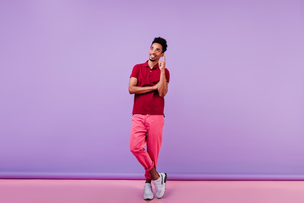 Foto gratuita hombre sonriente inspirado en camiseta roja disfrutando de interior. chico guapo con pie de pelo corto ondulado.