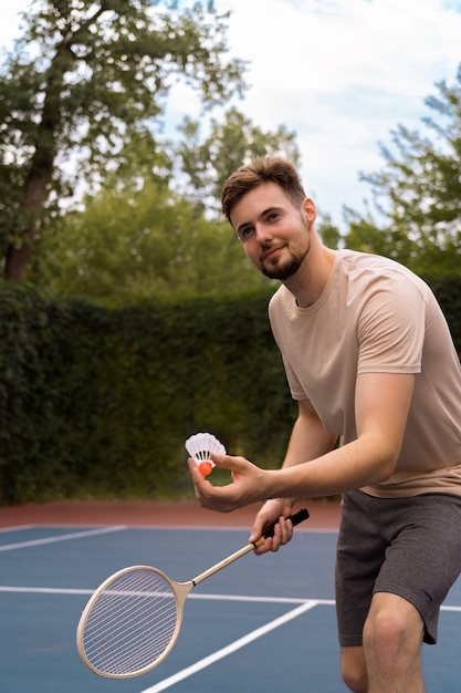 Hombre sonriente jugando bádminton vista lateral