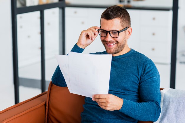 Hombre sonriente leyendo en casa documentos