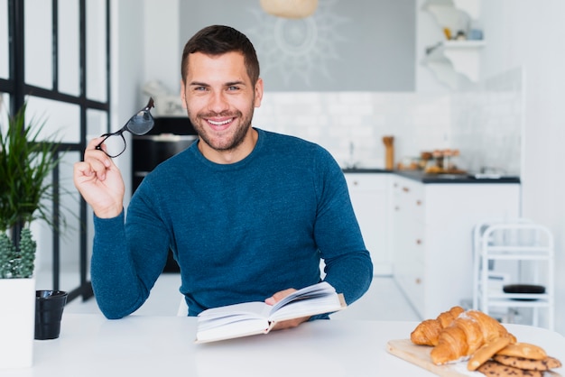 Foto gratuita hombre sonriente con libro mirando a cámara