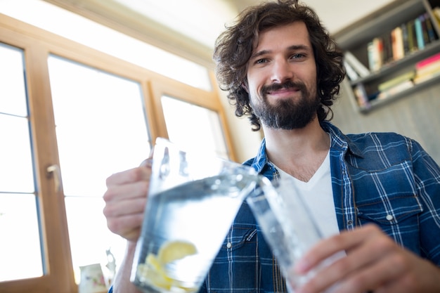 Hombre sonriente de la limonada que vierte en el vidrio