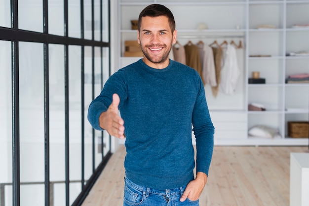 Hombre sonriente con la mano hacia la cámara para estrechar la mano