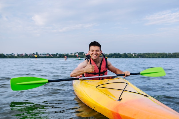 Hombre sonriente mostrando pulgar arriba signo mientras kayak