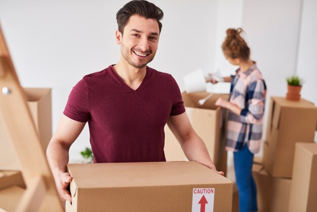 Hombre sonriente mudándose a casa nueva y desempacando sus cosas