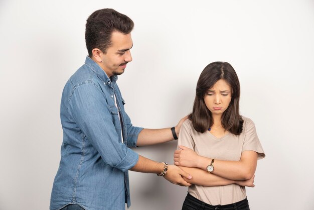 Hombre sonriente y mujer molesta en blanco.